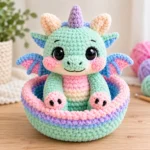 Dragon amigurumi pattern showing a mint-green pastel baby dragon with pink cheeks, blue wings and matching crochet basket