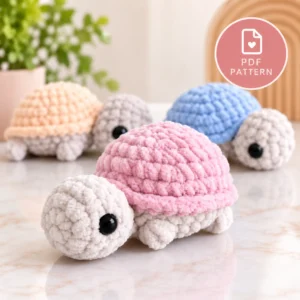 Crochet turtle pattern featuring a plush baby turtle with a soft pink textured shell, cream head and black safety eye