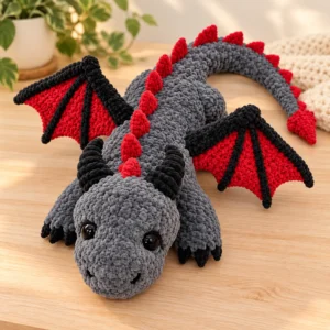 Dragon crochet pattern featuring a grey plush dragon with red wings, black horns and a spiked tail