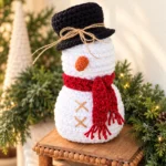 Crochet snowman pattern featuring a white wheat stitch snowman with grey top hat and light blue scarf