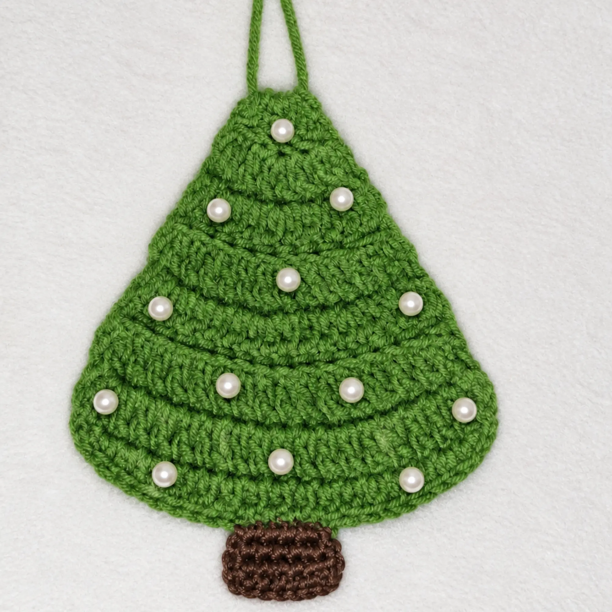 Crochet Christmas Tree Pattern PDF – Ornament & Garland Close-up of crochet Christmas tree ornaments in different green shades with pearl beads, brown trunks and red bows