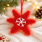 Red crochet star ornament with white snowflake embroidery hanging on a Christmas tree